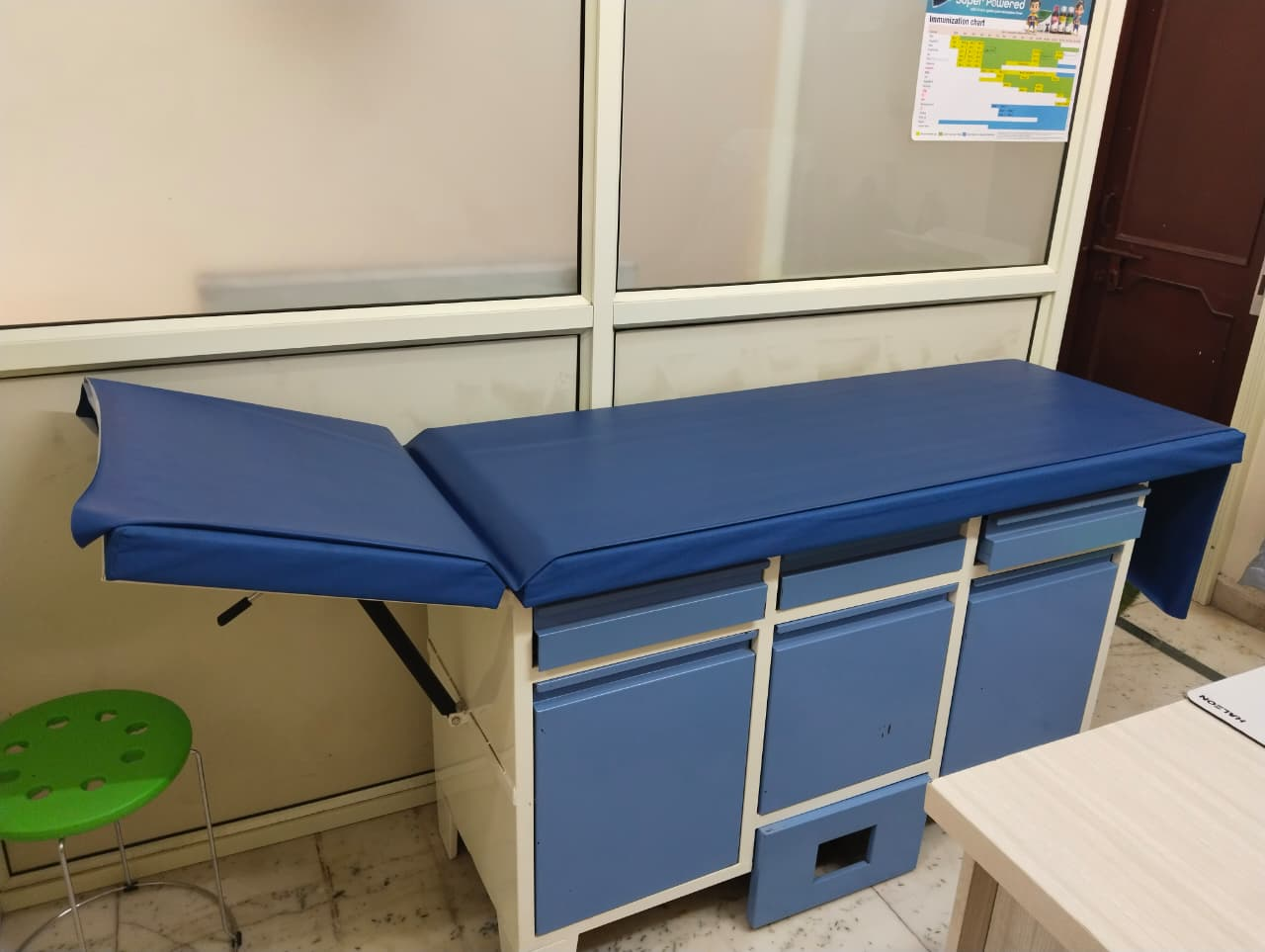 Clean vaccination area with examination table and immunisation chart at Wellnest Child Care Centre